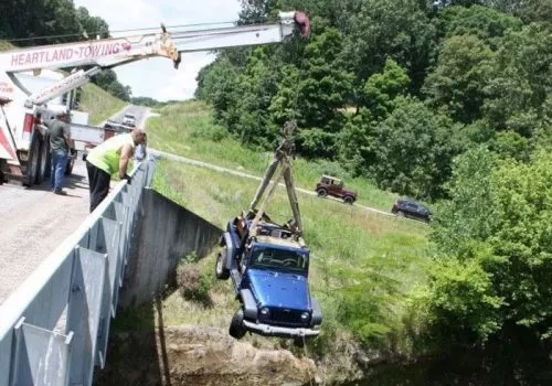 A truck using a crane to lift a jeep as part of recovery services in South Central Illinois