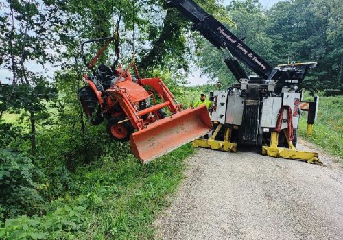 A tow truck pulling a tractor out of a ditch, part of Heartland's Towing Service for Mattoon IL