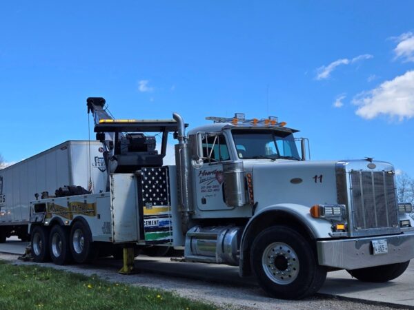 A Heartland Towing wrecker on the side of the road, preparing to help haul a semi-truck as part of heavy-duty towing services