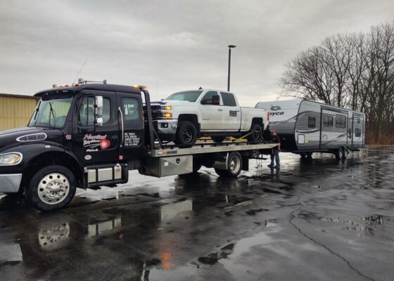 Heartland wreckers pulling a pickup truck and large RV, part of their reliable heavy-duty towing services