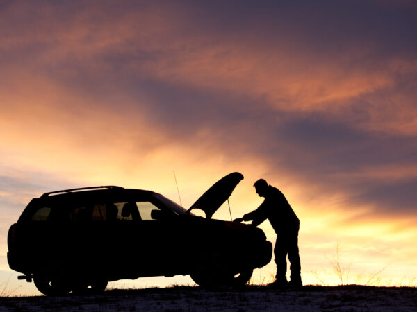 A silhouette of a man beside his vehicle before he calls for towing Vandalia IL services